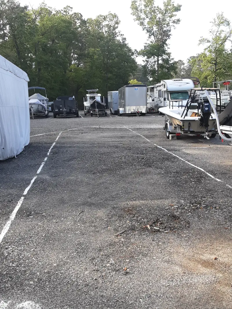 A boat on a trailer is parked in a storage lot at Matthews Boat and RV Storage.